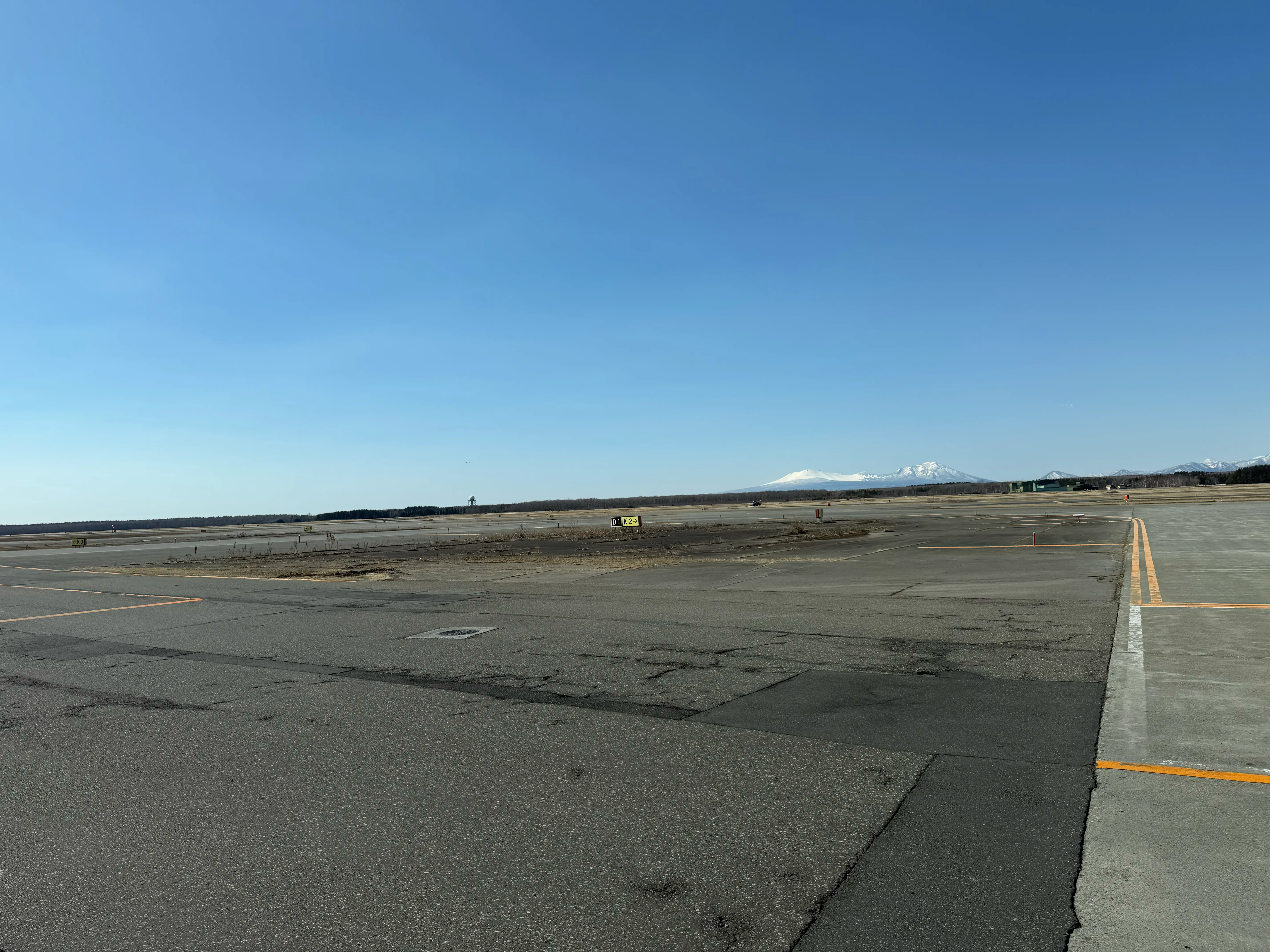 新千歳空港の滑走路と快晴の青空。遠くに雪をかぶった山々が見える