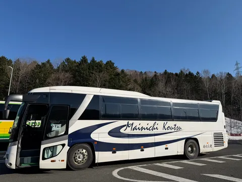 毎日交通のシャトルバス。青空のもとに停車する白と紺のバス
