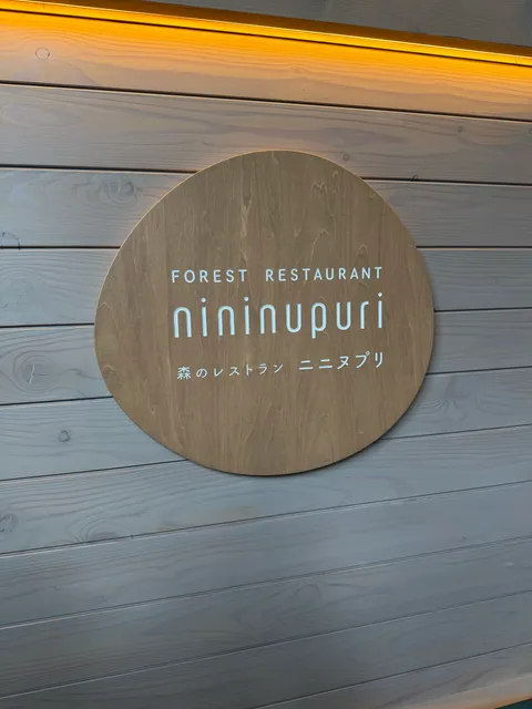 床に埋め込まれた森のレストラン nininupuri の円形看板。落ち着いた木目調のデザイン