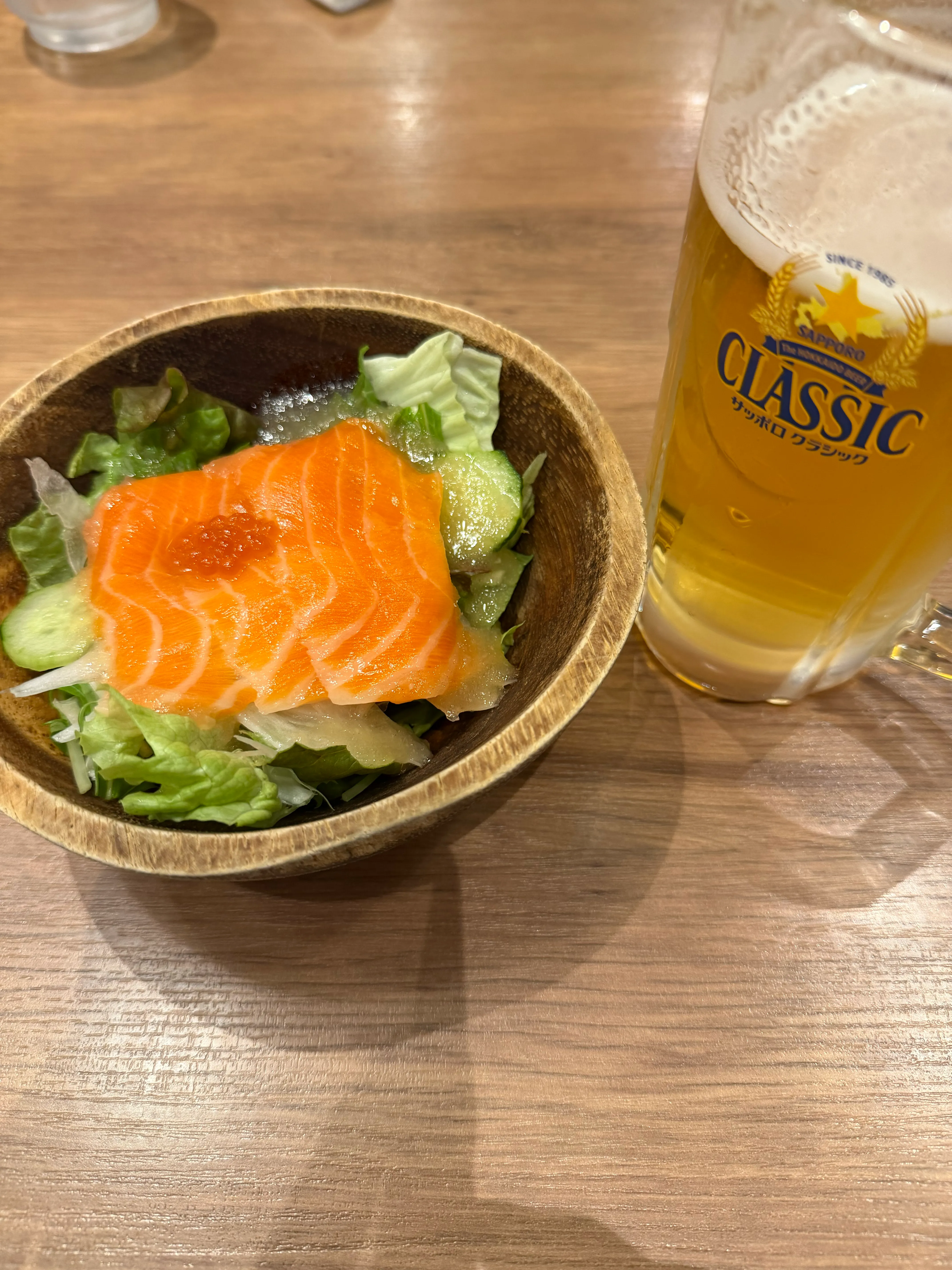 サーモンとイクラのサラダとビール。グリーンの上に鮮やかなサーモンとイクラが乗る