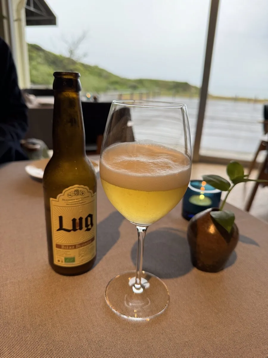 糸島産クラフトビール「Lug」とワイングラス。窓の外に緑が広がる