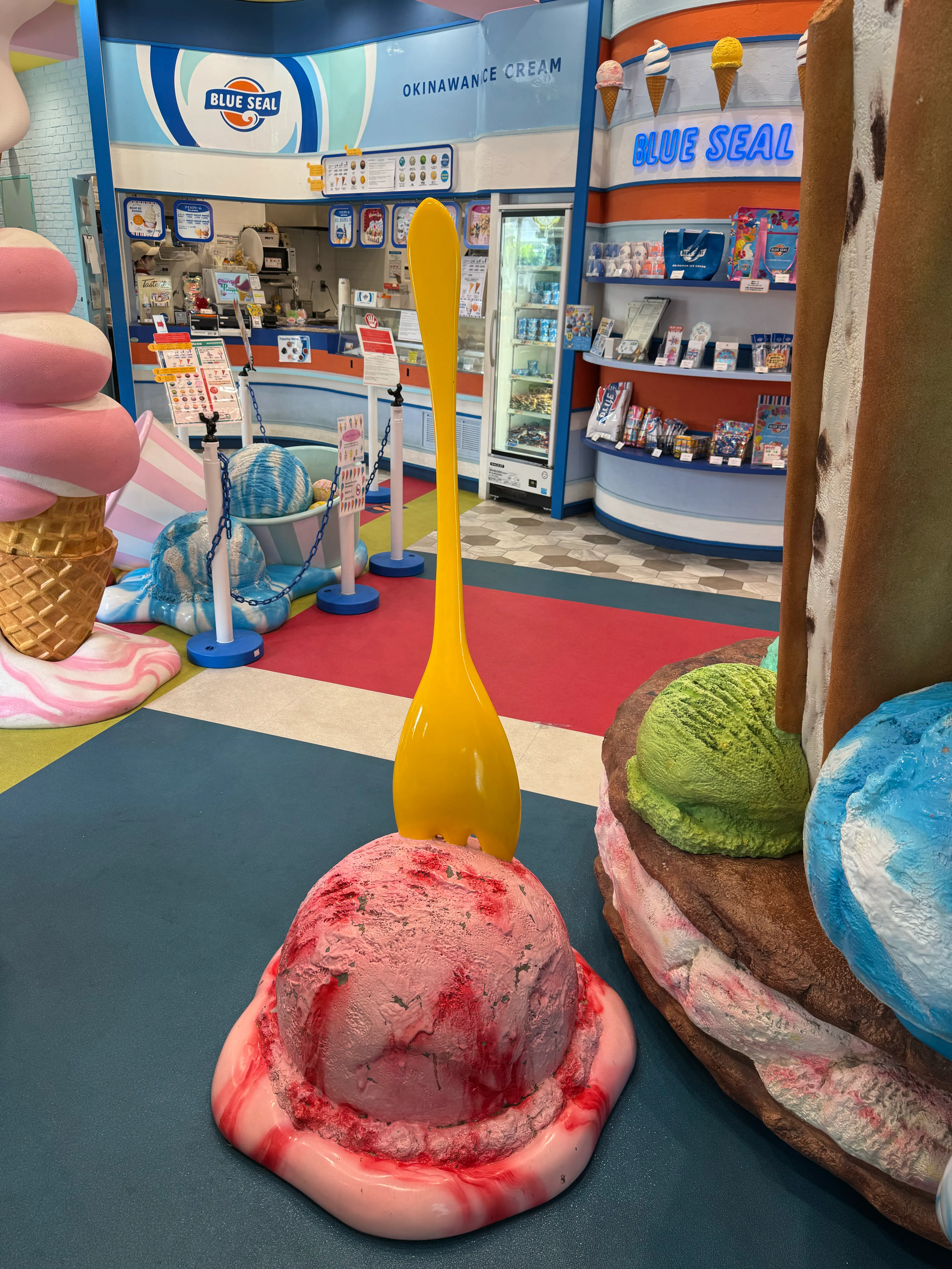 ICE STANDオブジェ越しに見えるブルーシールカウンターと「OKINAWAN ICE CREAM」看板