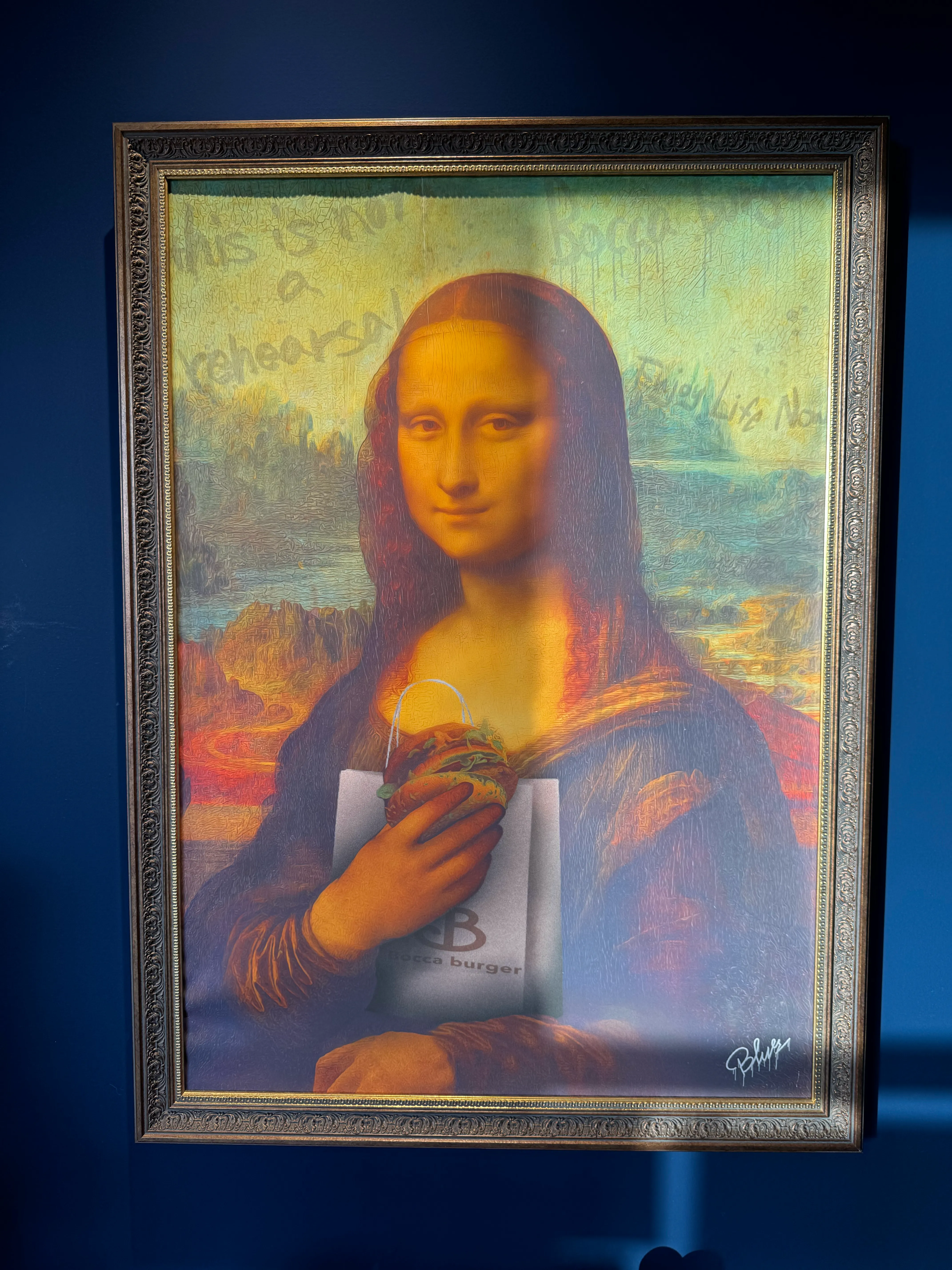 モナリザがハンバーガーを持つパロディ絵画。額縁に入って飾られている