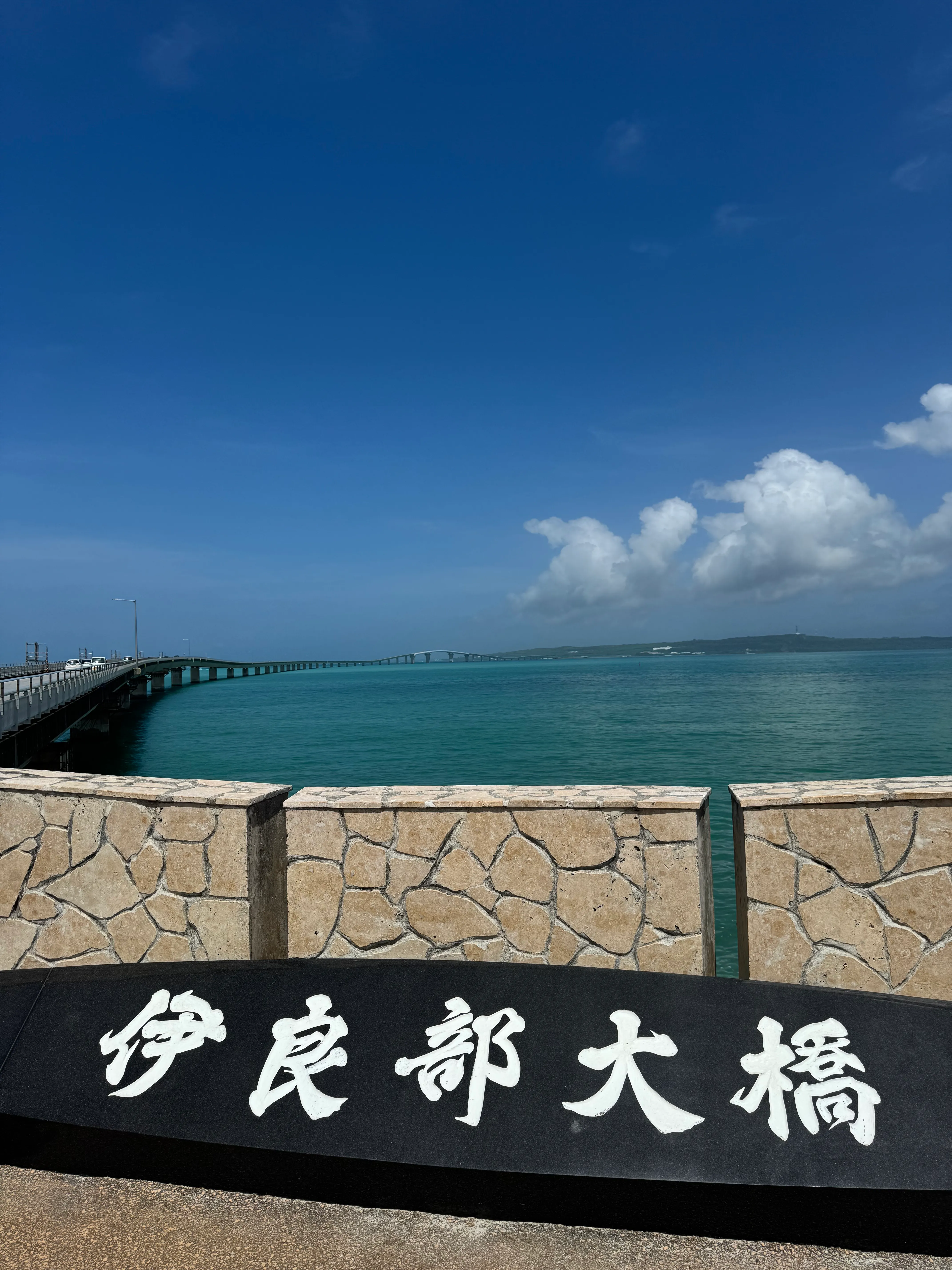 橋のたもとから望む伊良部大橋の看板と宮古ブルーの海