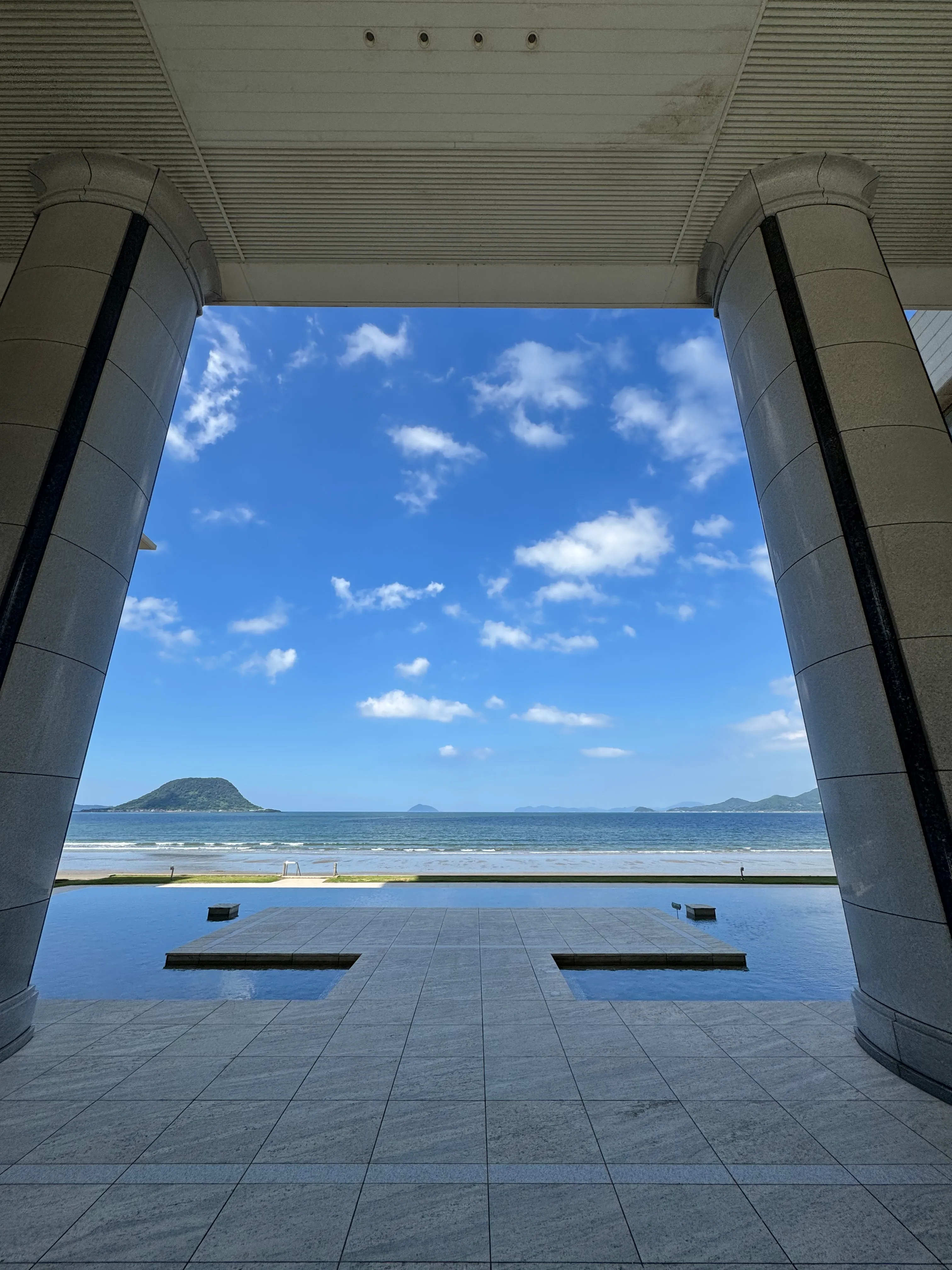 唐津シーサイドホテルの窓枠越しに見える青空と唐津湾。建物の躯体と海と空が一枚の絵のように収まっている