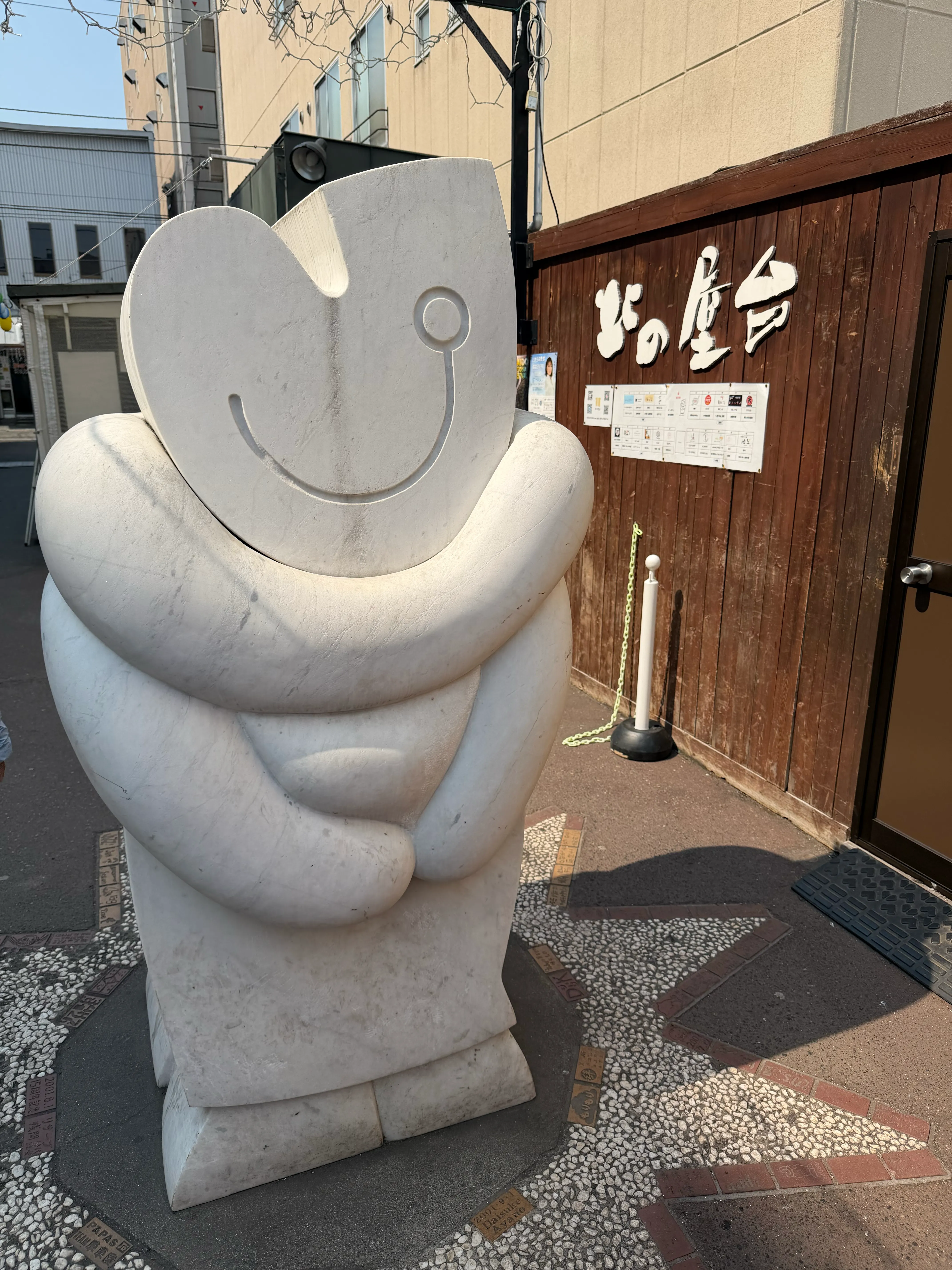 北の屋台の入口前に置かれた白い抽象彫刻。丸みを帯びた形状で、にっこりと笑っているような表情がある