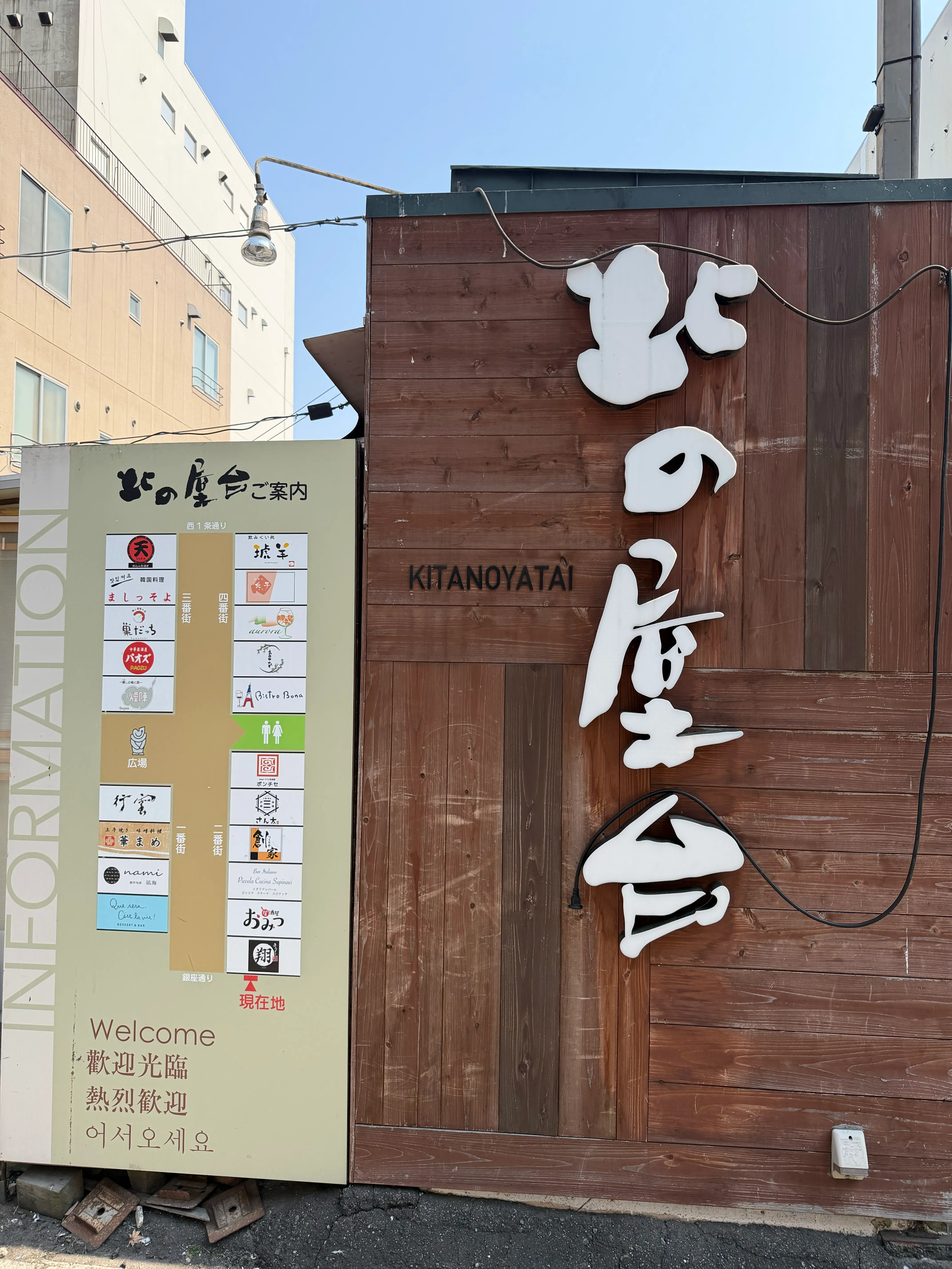 北の屋台の入口看板。木製の外壁にKITANOYATAIの文字と、出店店舗一覧のインフォメーションボードが並んでいる