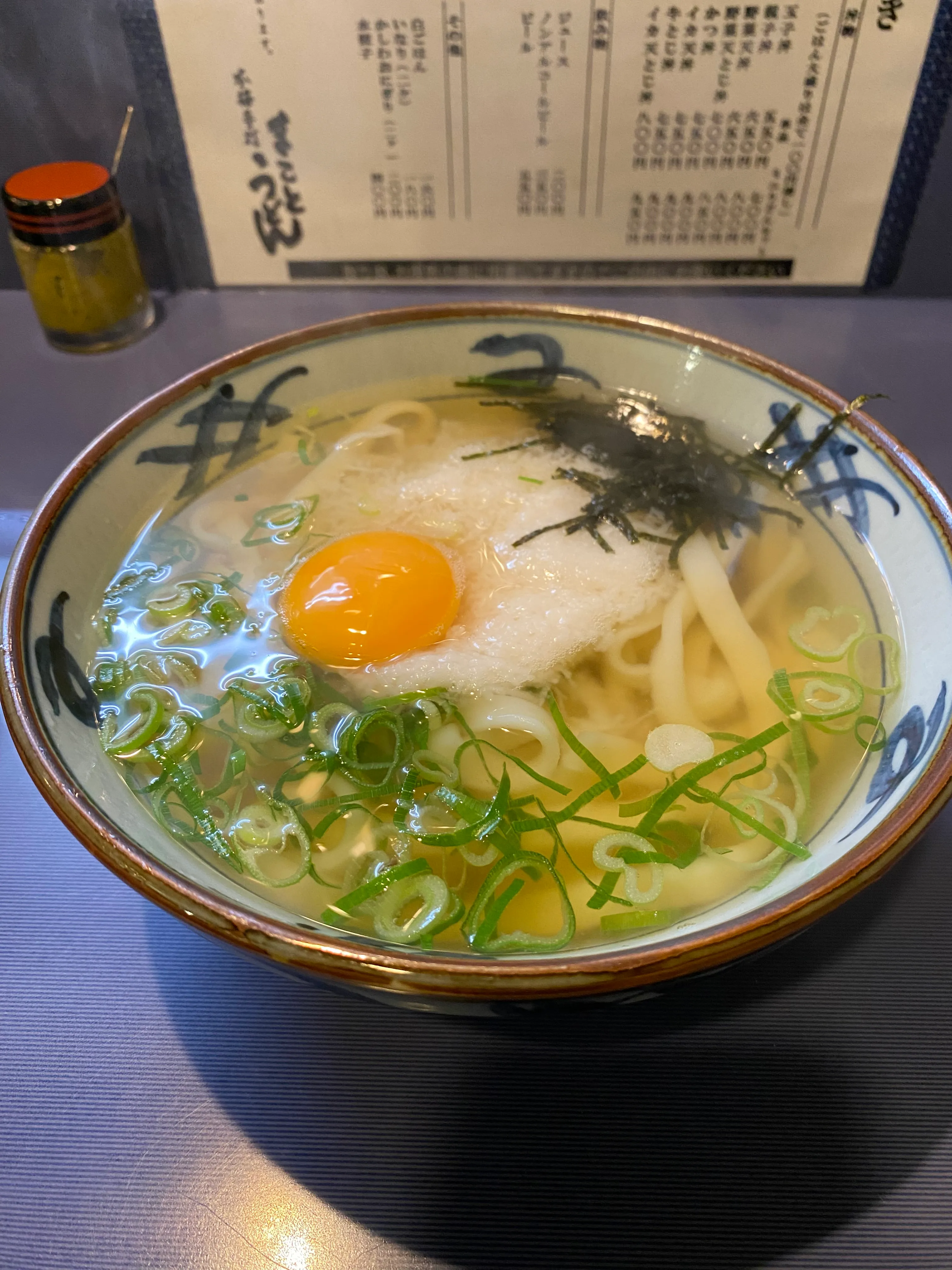 まことうどんのうどん。透き通ったスープに生卵・大根おろし・ネギ・海苔が乗った美しい一杯