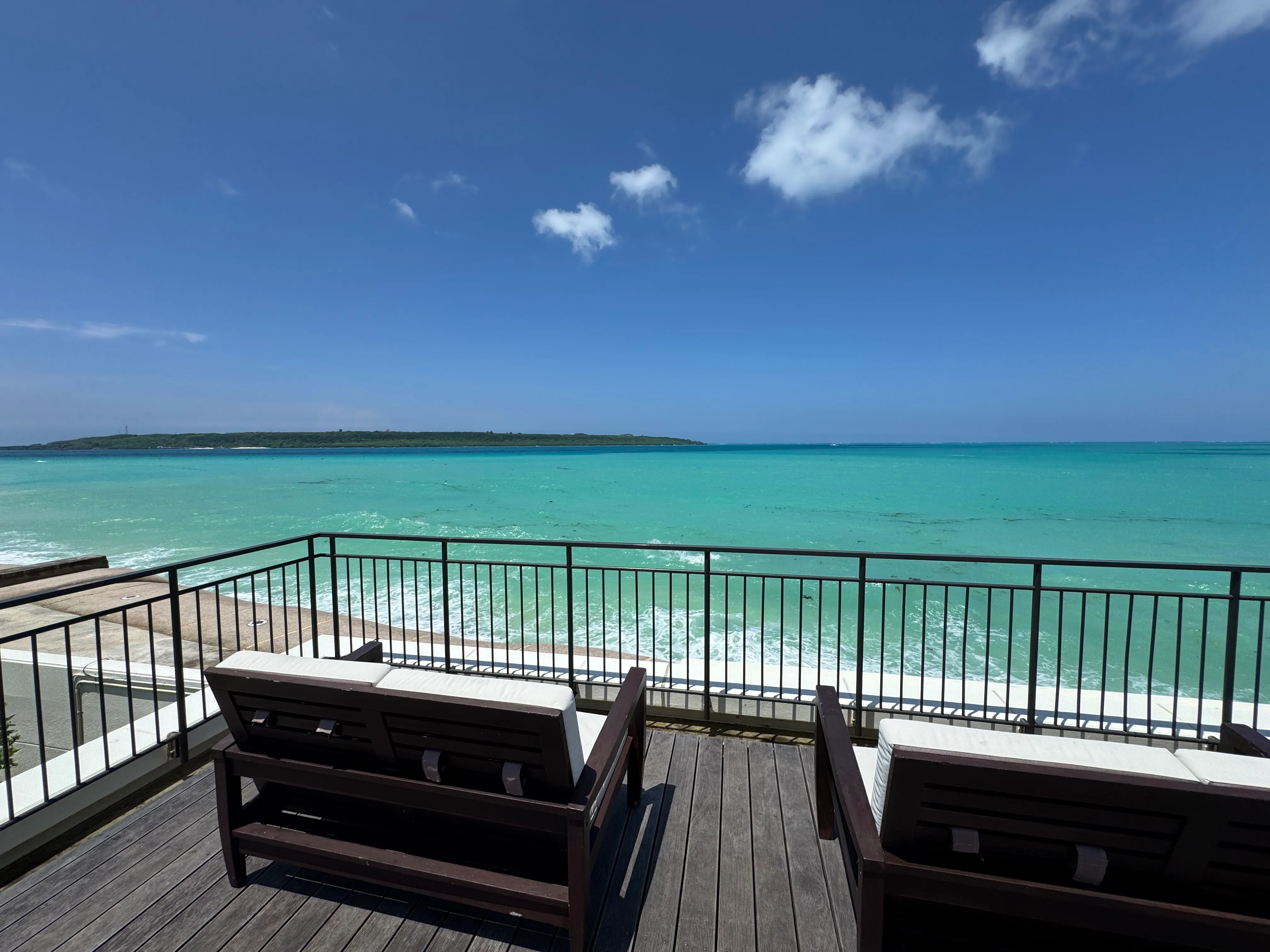 テラスから見えるエメラルドグリーンの海とビーチチェア