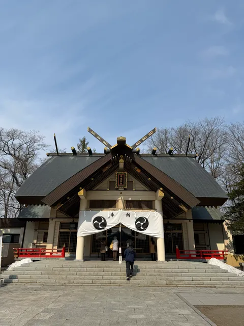 帯廣神社の拝殿正面。三つ巴の神紋が入った大きな白い幕が下がり、青空が広がっている