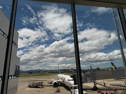 福岡空港のターミナルガラス越しに見えるスカイマークの航空機と夏の積乱雲