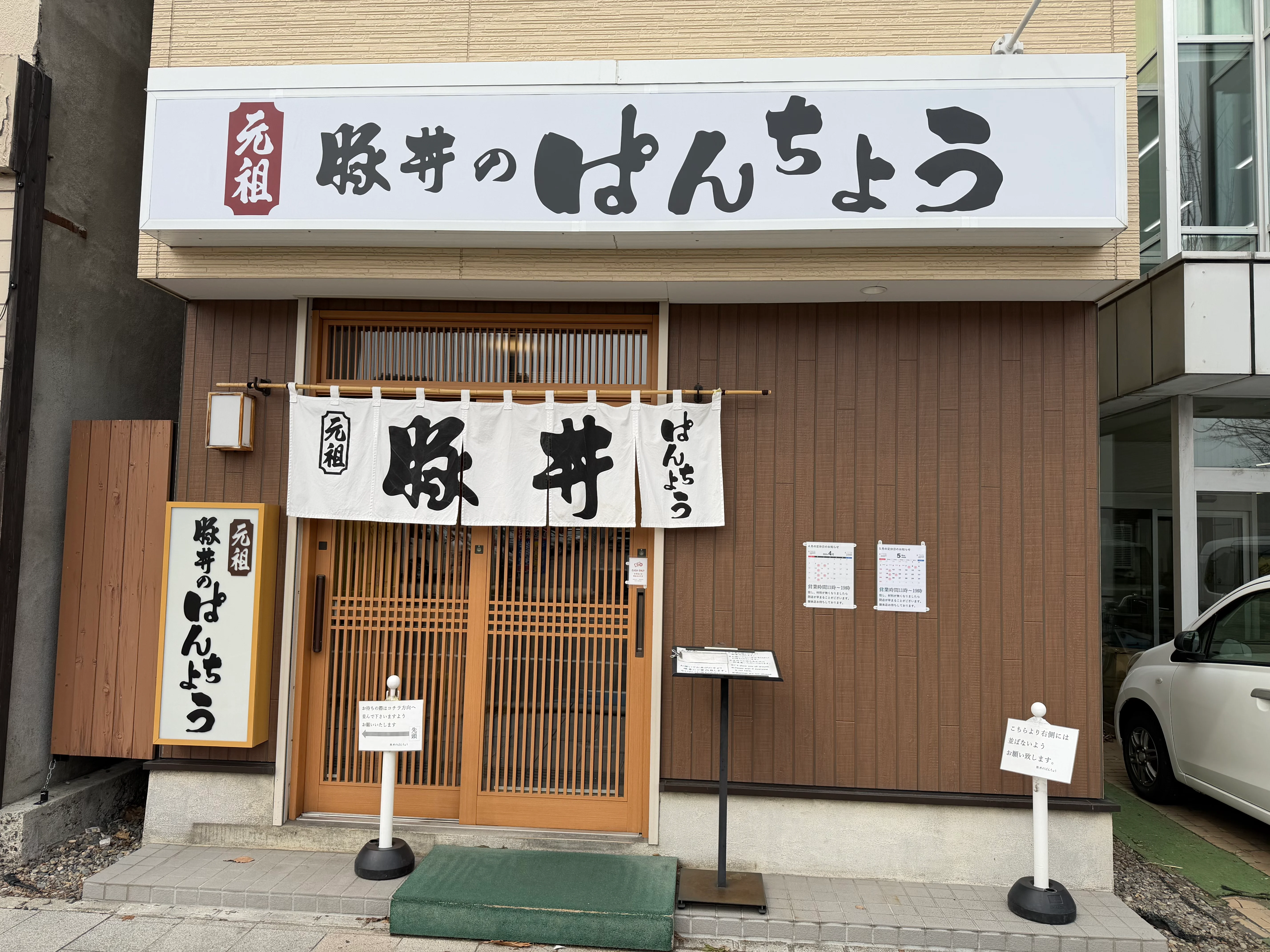元祖 豚丼のぱんちょうの店外観。白い暖簾に「元祖 豚丼」の文字