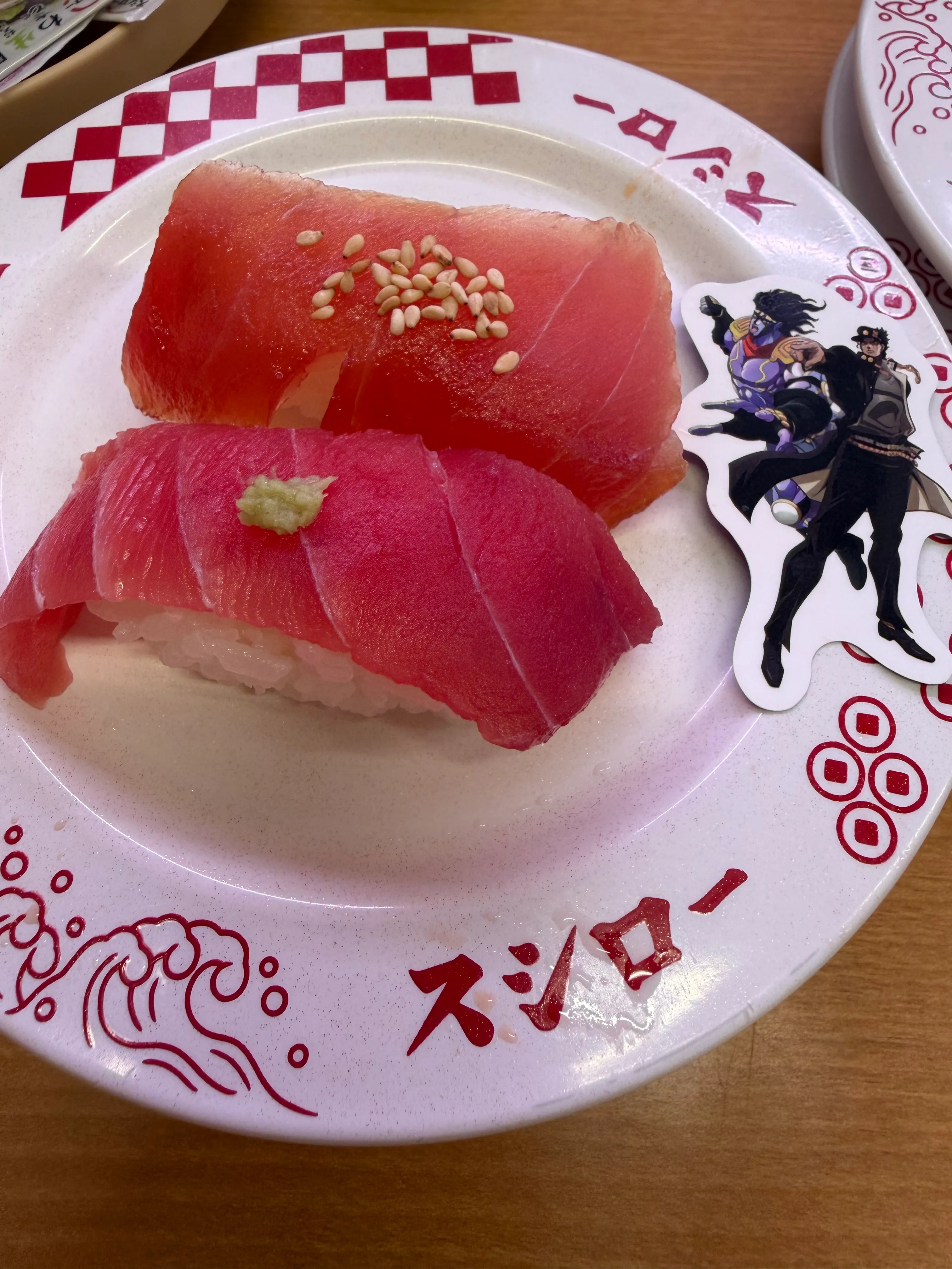 コラボ皿にのったマグロ2貫。DIO系キャラのジョジョピックが刺さっている