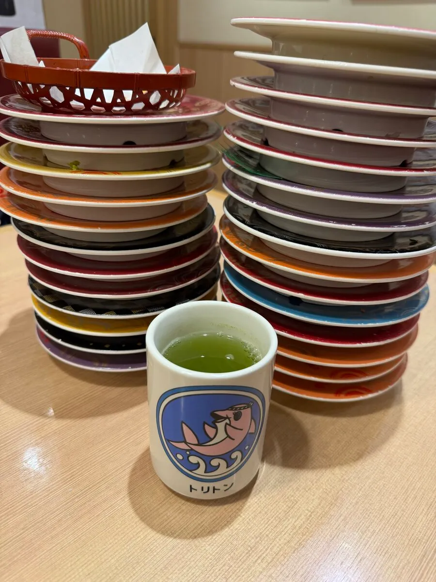 食後に積み上がったトリトンの皿の山とロゴ入り湯呑み